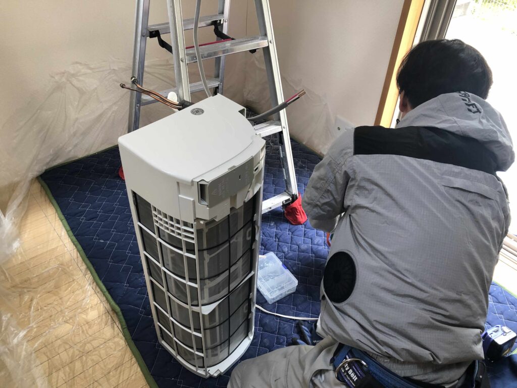 スタッフがエアコン室内機の取り付け準備をしている様子
